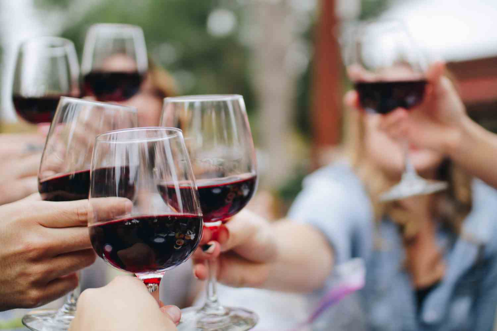 Hands clinking red wine glasses during a festive gathering, the perfect tailgating wine moment