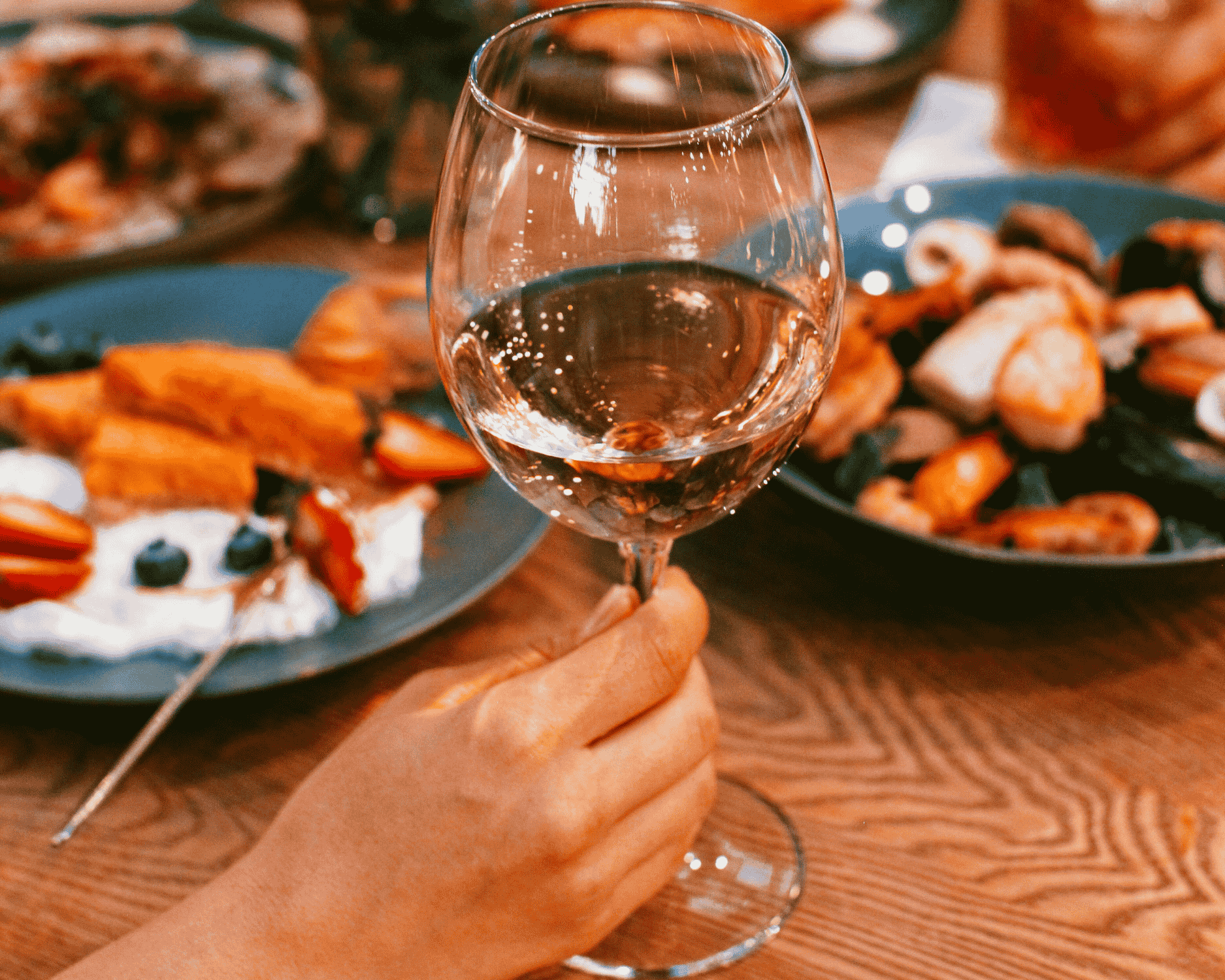Glass of orange wine served with a fall-inspired dinner, showing ideal food pairings and serving tips for orange wine