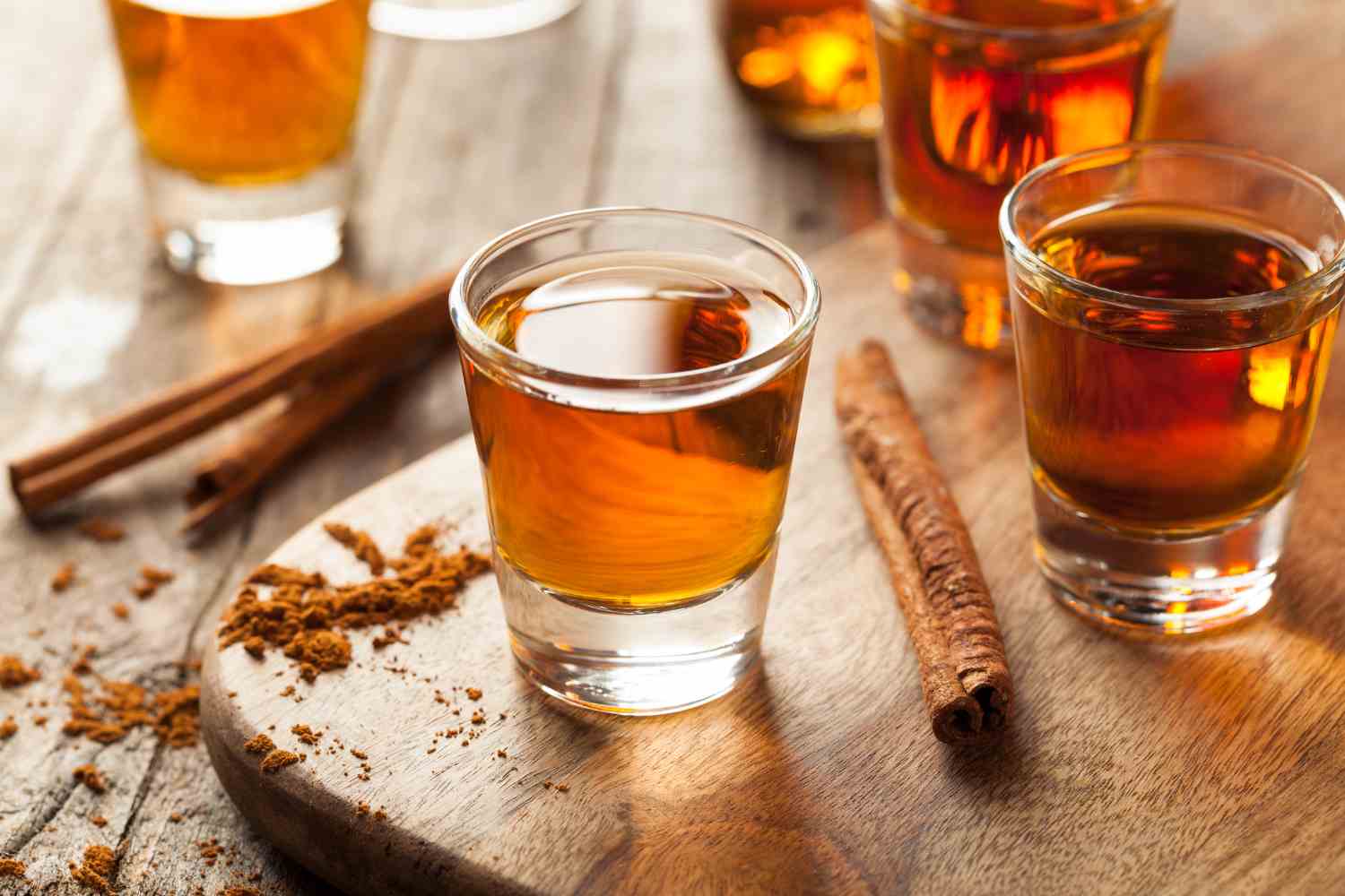 Assorted bourbon bottles on a rustic table with fall leaves, showcasing unique bourbons for the autumn season