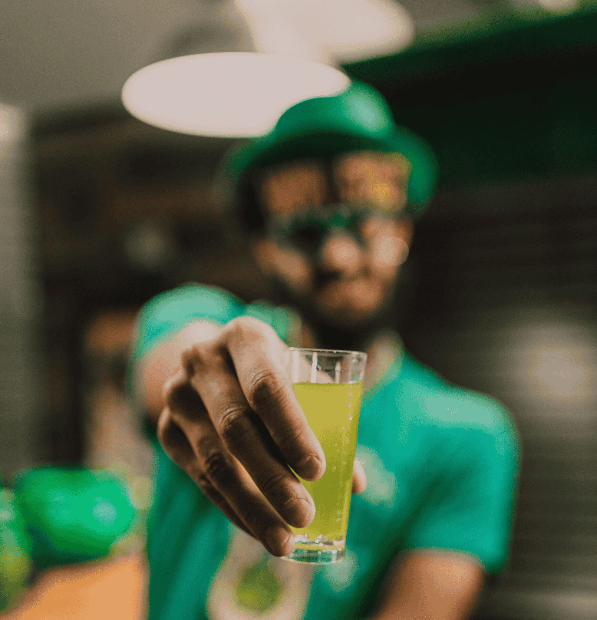 Person holding a green cocktail shot made with Irish whiskey, celebrating with a festive Irish drink for St. Patricks Day