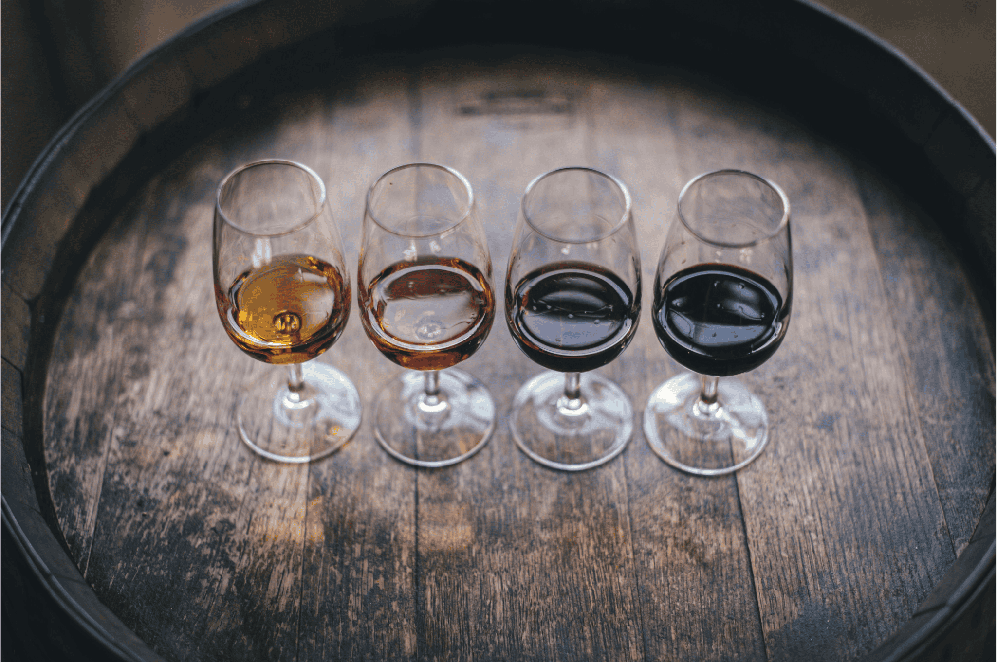 Four glasses of wine in different shades on a rustic barrel