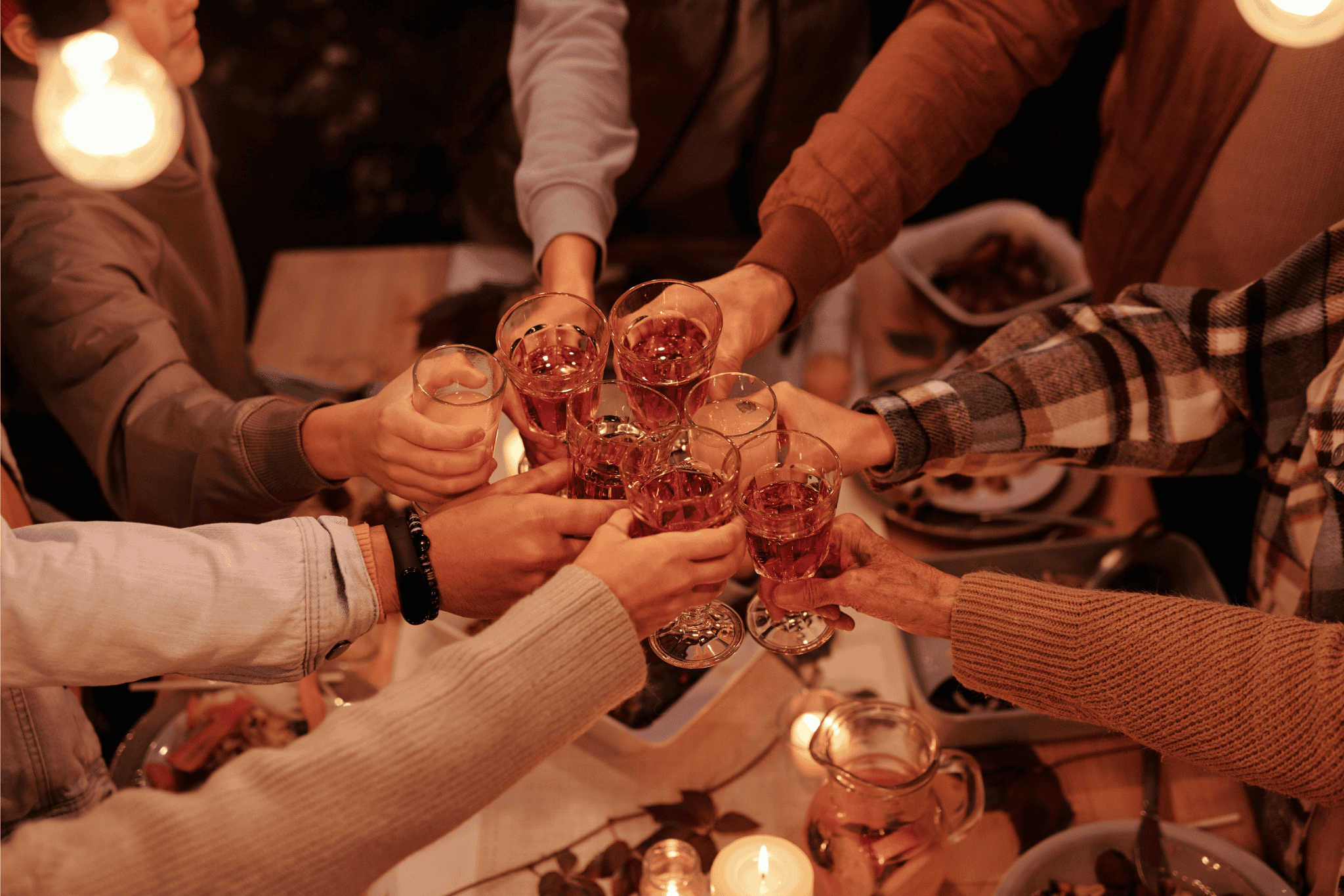 Friends raising glasses of wine around a cozy dinner table