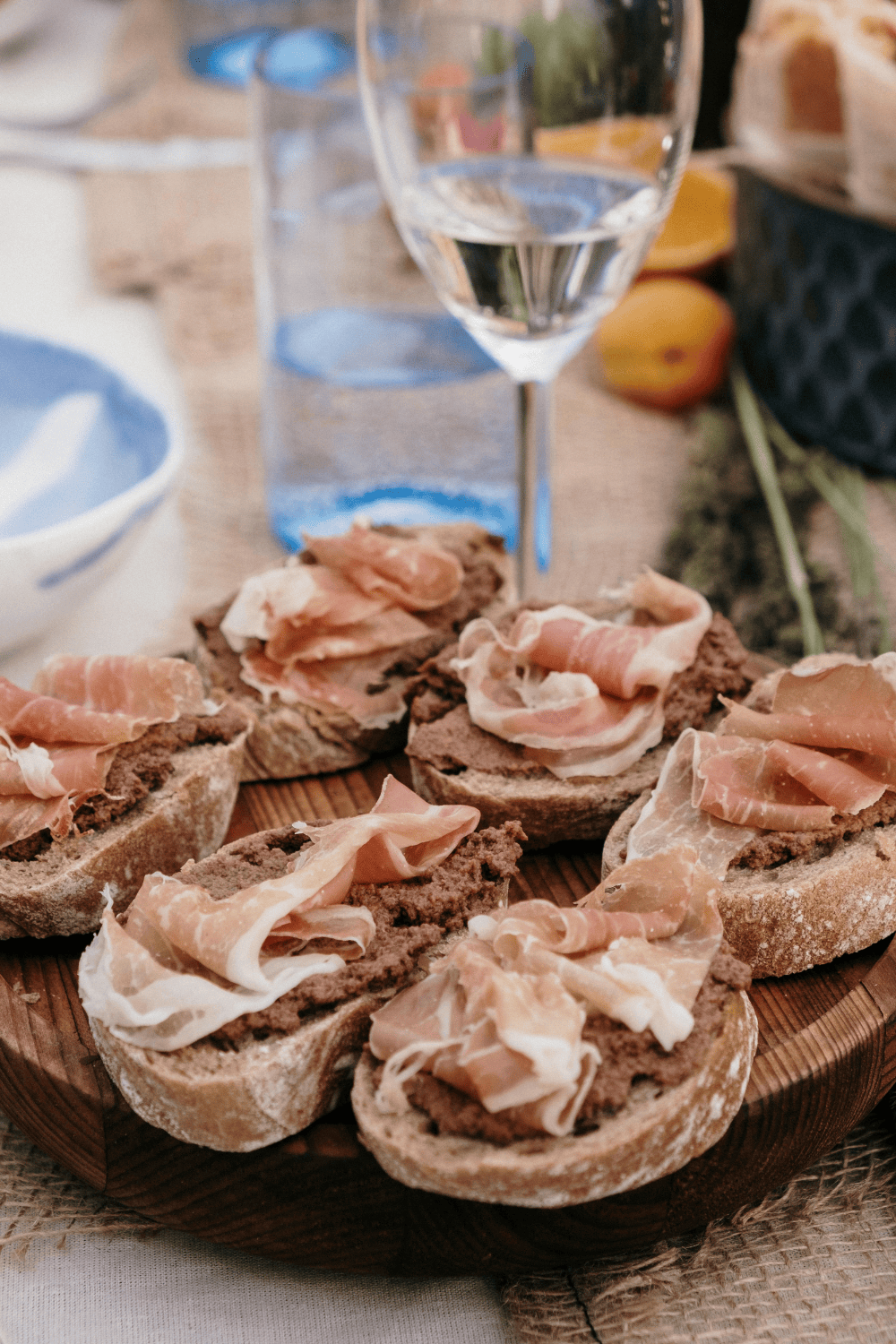Cured meat crostini paired with a glass of white wine, perfect for wine and deli pairings or elegant wine and food pairings